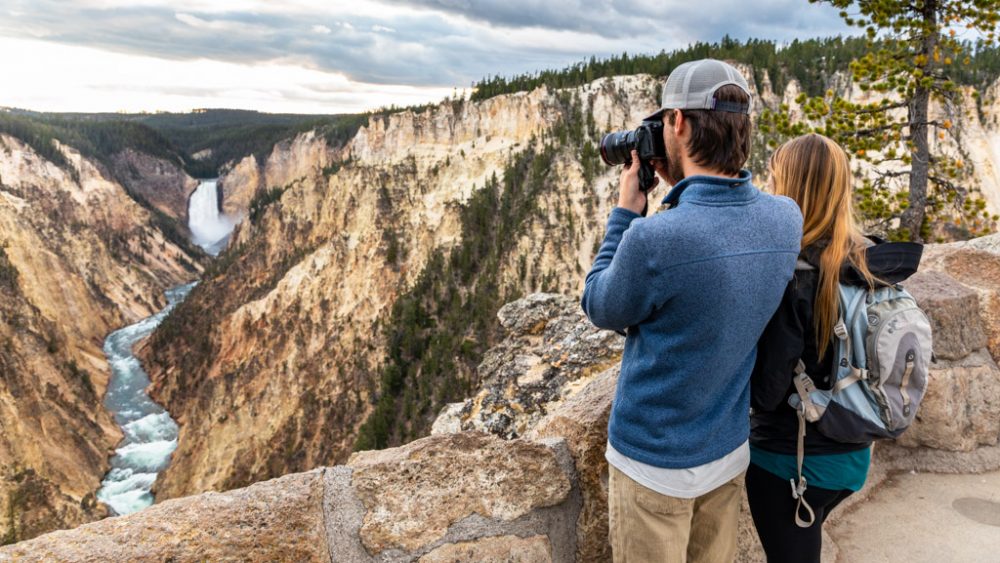 A couple taking photos of the Grand Canyon of the Yellowstone from Artist Point.